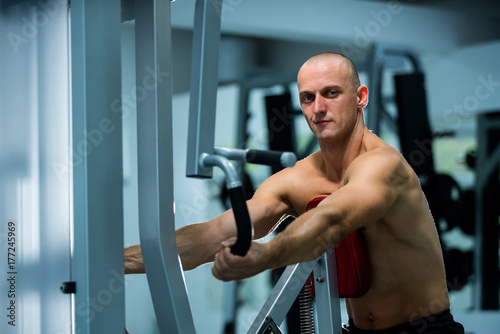 Adult muscle man using gym machines for working out