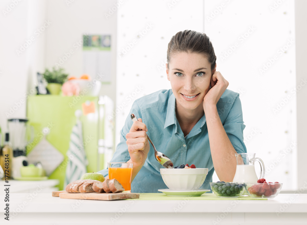 Smiling woman having breakfast at home