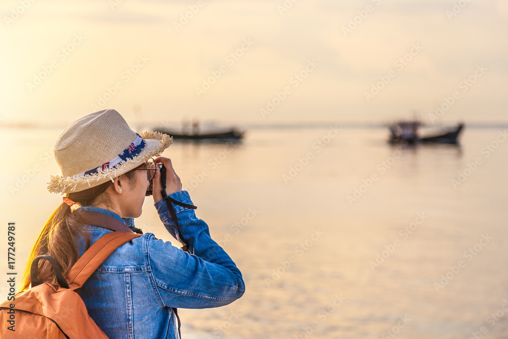 Women travelers happy traveling and taking photo with digital camera to the beauty of the city and the sea in his holidays During his time at sunset for Post to Online on the Internet.