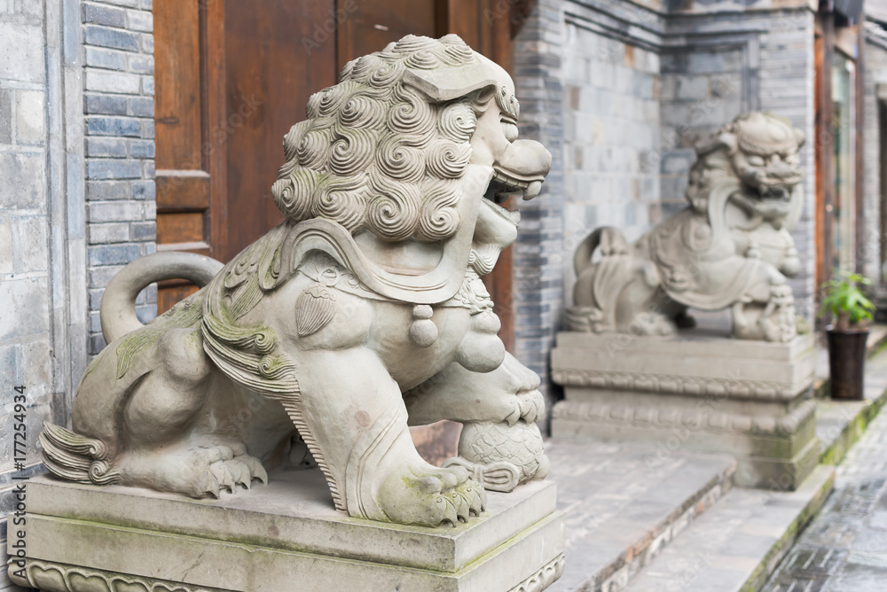 Two lion stone statues in front of a wooden door in KuanZhai narrow alley, Chengdu, China