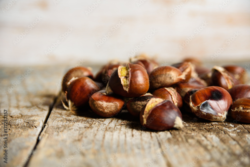 Roasted chestnuts on old wooden table. close up and selective focus. Autumn background 
