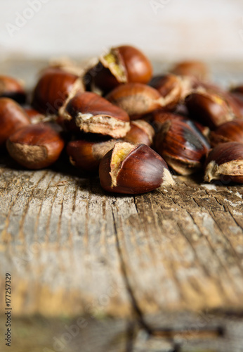 Roasted chestnuts on old wooden table. close up and selective focus. Autumn background 