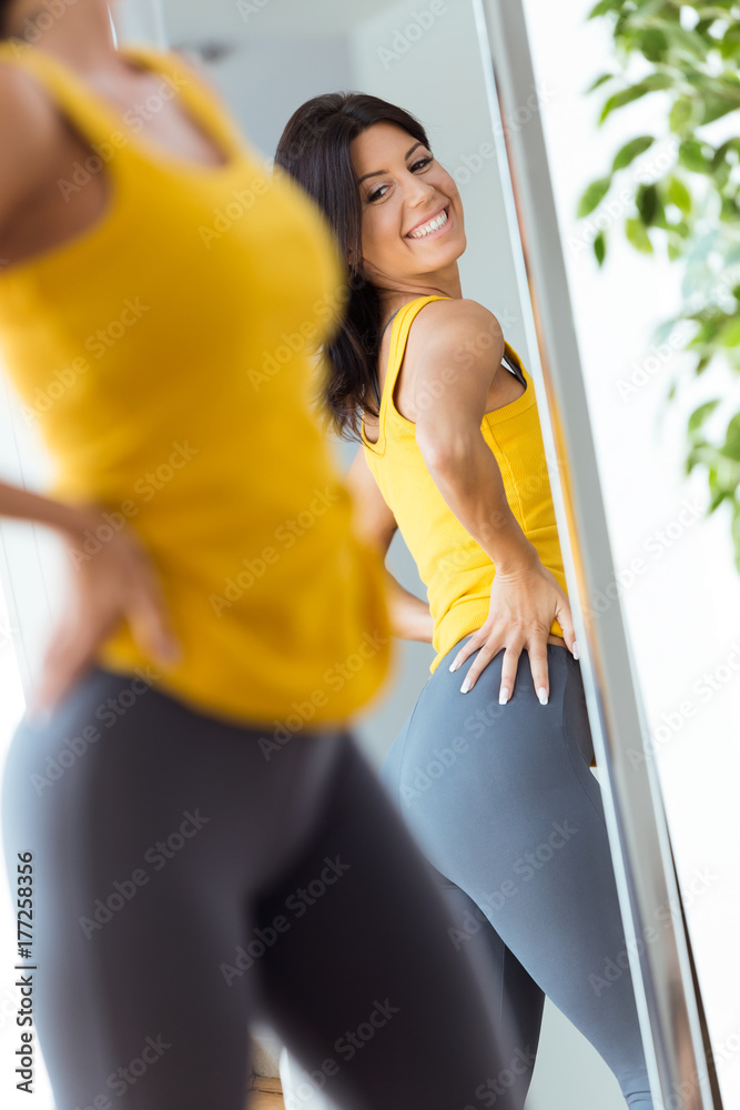 Obraz premium Beautiful young woman looking herself reflection in mirror at home.