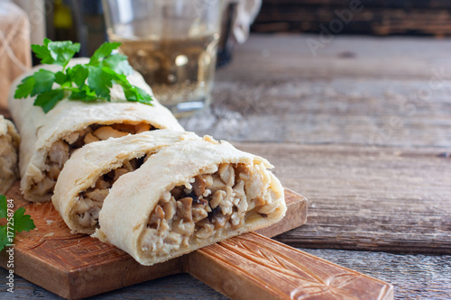 Snack chopped strudel with mushrooms, cheese and chicken on a wooden board, horizontal, copy space. Rustic style. photo