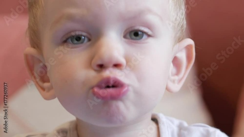 Cute funny boy pulls his lips and laughs. Home decor in the background. Close-up