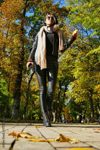  beautiful girl in leather trousers strolls through the autumn park photo