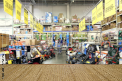 Shop of garden equipment. Lawn mowers. Defocused image. In the foreground is the top of a wooden table or counter.