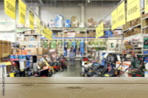 Wallpaper Mural Shop of garden equipment. Lawn mowers. Defocused image. In the foreground is the top of a wooden table or counter. Torontodigital.ca