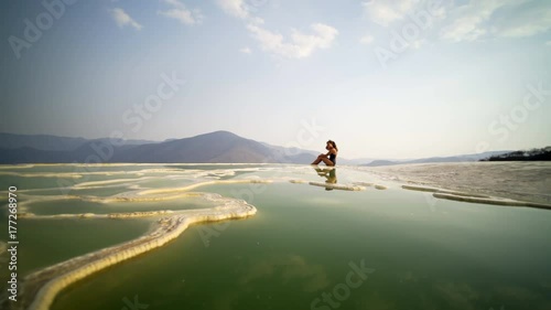 panoram on mineral nature pool with young women siting on the beautiful view, Mexico Hierve el Agua