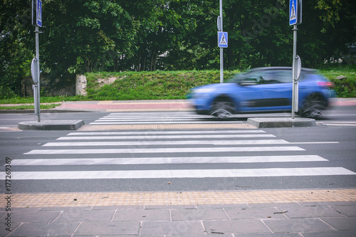 A blue car passing crosswalk