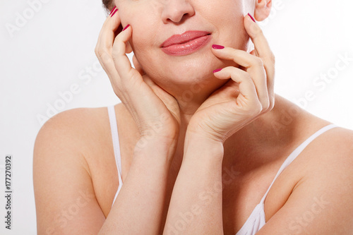 Beautiful smiling woman face close up isolated. Anti age concept. Collagen and plastic surgery. Female touching her face. Red manicure. Mock up and copy space. Cropped image