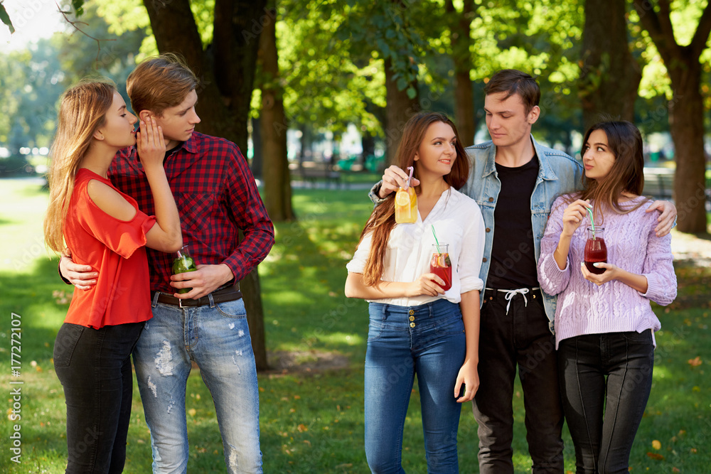 Jealousy and envy in friends relationship. Cheerful young people with detox cocktail having outdoor summer party Jealousy and envy in friends relationship. Cheerful young people with detox cocktail having outdoor summer party