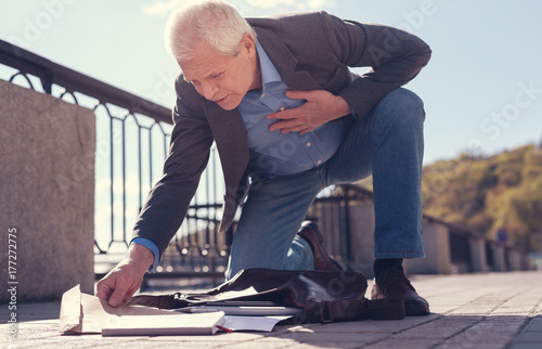 Senior man with sore heart gathering his scattered belongings