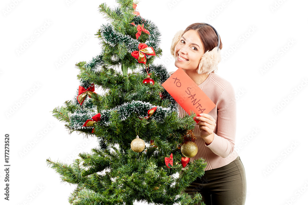 Portrait of beautiful woman in earmuffs posing near Christmas tree Portrait of beautiful woman in earmuffs posing near Christmas tree
