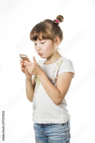 A young girl with blond hair is holding phone and sends a kiss message over the phone. white isolated background