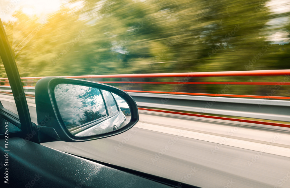 The reflection in the rear-view mirror of car in motion