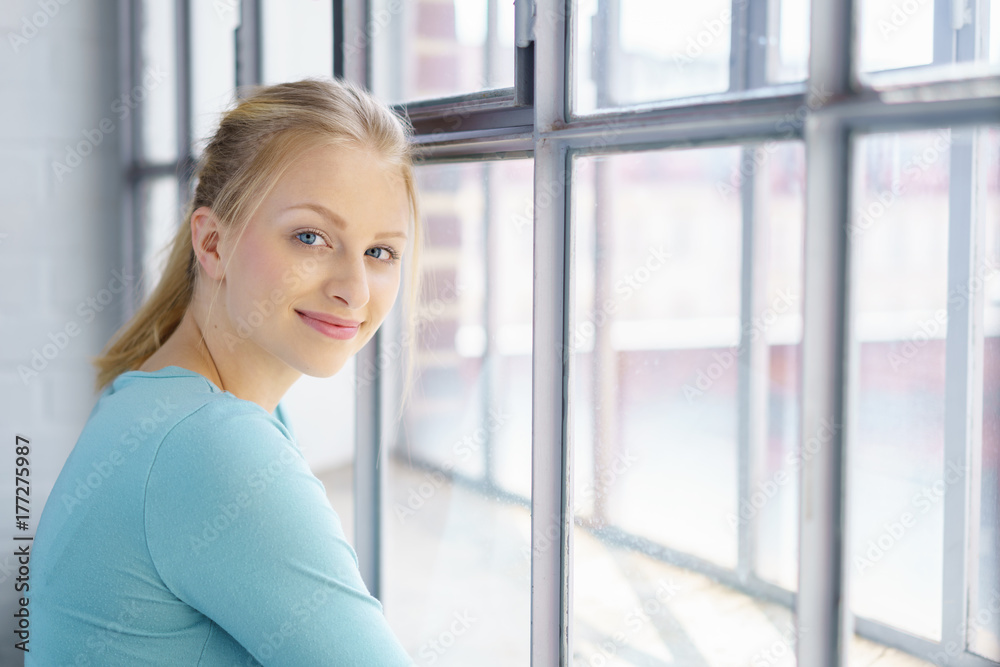 sympathische junge frau steht am fenster sympathische junge frau steht am fenster