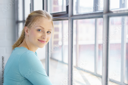 sympathische junge frau steht am fenster