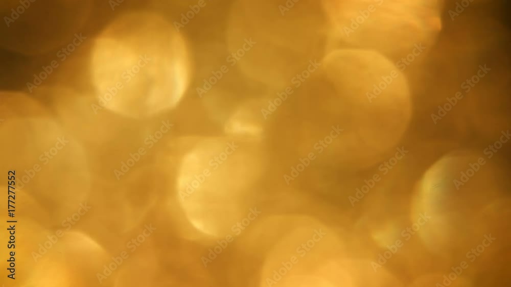 Soft, gentle, shimmering golden bokeh. Rich warm shifting light elements against a gold background. A magical effect. Kind of like rippling water. 