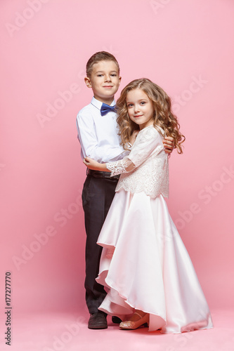 Boy and girl standing in studio on pink background