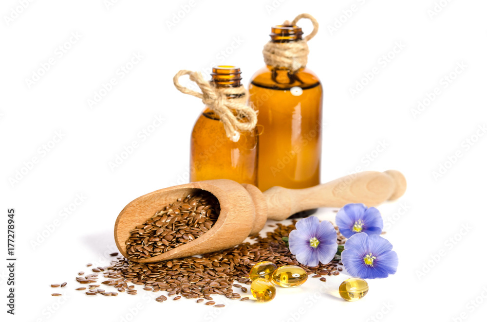 Flax seeds in the wooden scoop, bottle with oil and beauty flowers isolated on white background. Flax seeds in the wooden scoop, bottle with oil and beauty flowers isolated on white background.