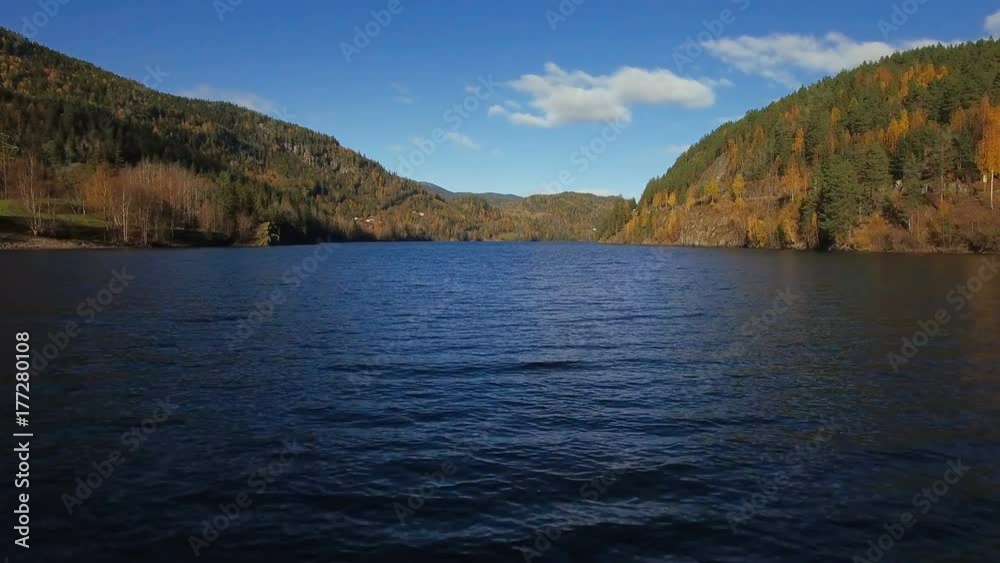Flying low over the rippled water of beautiful lake towards colorful autumn mountains with trees at daylight. 4K Aerial footage. Norway. Flying low over the rippled water of beautiful lake towards colorful autumn mountains with trees at daylight. 4K Aerial footage. Norway.