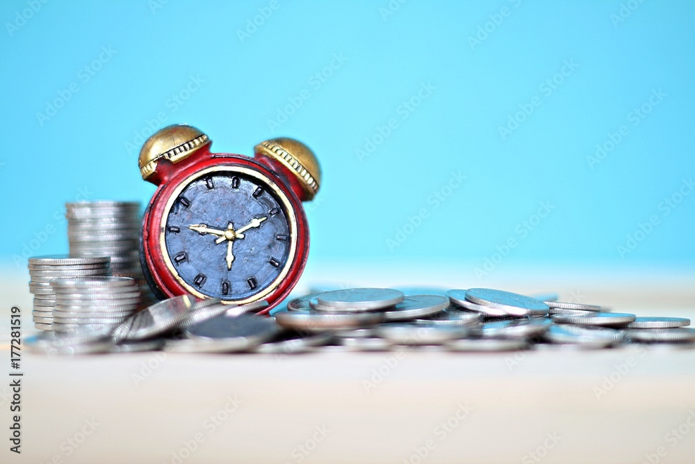 Business, finance, saving money and time concept : Miniature clock and coins stack on desk table Business, finance, saving money and time concept : Miniature clock and coins stack on desk table