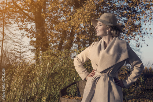 beautiful woman in a coat hat and a white dress for a walk in an autumn park or forest.