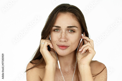 Stunning woman with earphones listens to the music on white background