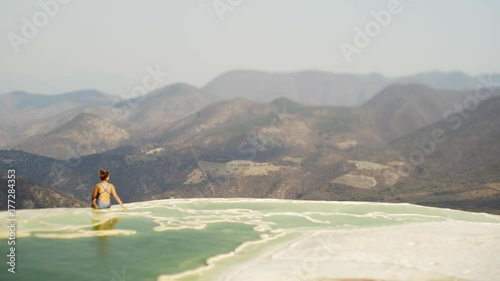  beautiful view with young girl sitting on the brink of mineral  pool, Mexico Hierve el Agua