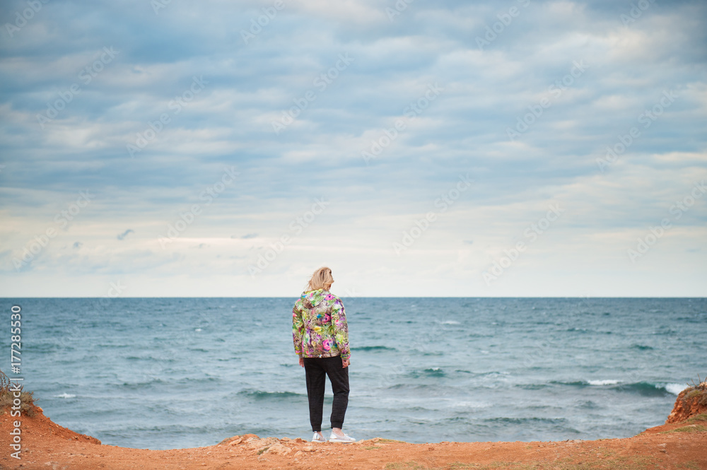 adult woman wearing colorful jacket walking by the autumn sea
