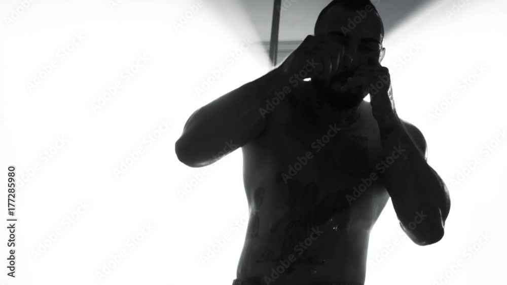 Strong professional boxer training in ray of light super slow motion black and white Strong professional boxer training in ray of light super slow motion black and white