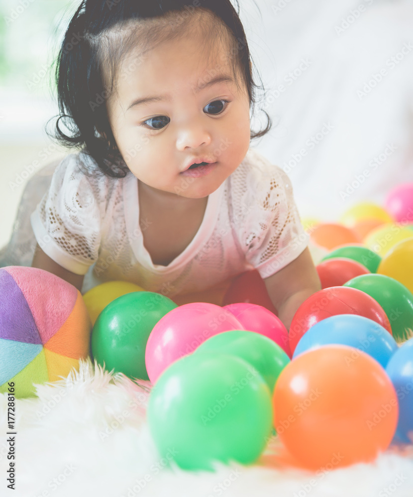 Obraz premium An Asian baby girl is playing in her bed with a happy expression.