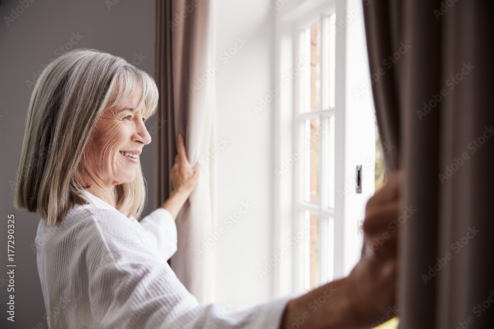 Senior Woman Opening Bedroom Curtains And Looking Out Of Window Senior Woman Opening Bedroom Curtains And Looking Out Of Window