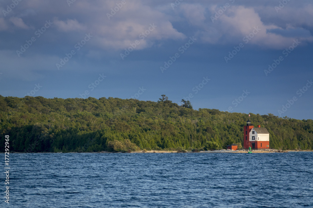 Beautifully restored Historic Round Island Lighthouse on Mackinac Island Michigan. Its bright colors stand out dramatically surrounded by the blue waters and pine tree forest  of Lake Huron.