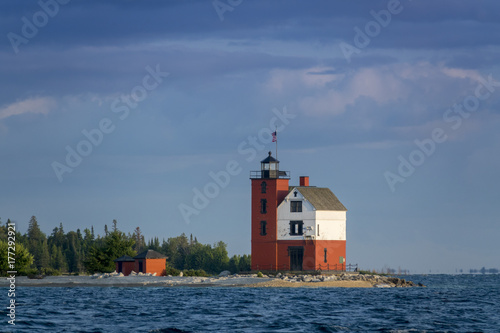 Beautifully restored Historic Round Island Lighthouse on Mackinac Island Michigan. Its bright colors stand out dramatically surrounded by the blue waters and pine tree forest  of Lake Huron.