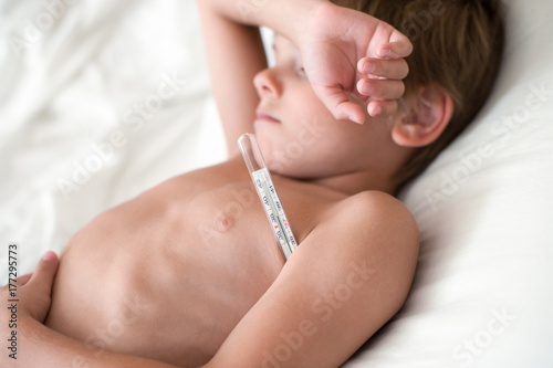 suffering from the disease child lying with a thermometer in the armpit