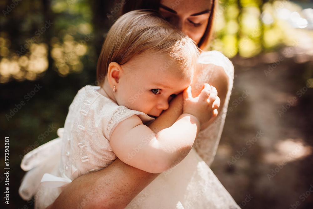 Little girl hides her face sitting on mother's arms Little girl hides her face sitting on mother's arms