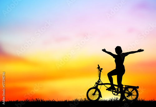 silhouette girl with a bicycle at blurry sunset.
