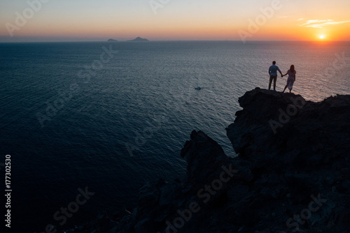 silhouette of a couple at sunset on a cliff overlooking the sea