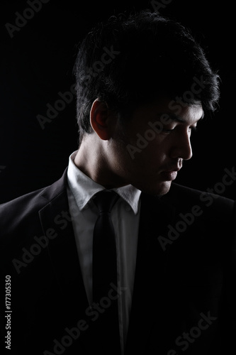 Asian man in black fomal suit in the dark