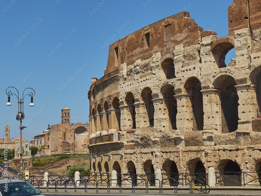 The roman Colosseum (also known as Flavian Amphitheatre) with the Temple of Venus and Rome and Santa Francesca Romana bell tower in background. View from Via Celio Vibenna. Rome, Lazio, Italy.