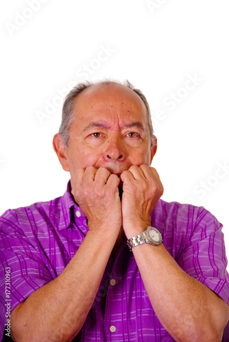 Portrait of a nervous mature man, with both hand in his mouth, wearing a purple square t-shirt in a white background