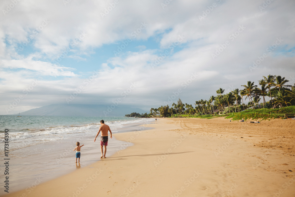 Young dad having fun running with toddler son on tropical beach Young dad having fun running with toddler son on tropical beach
