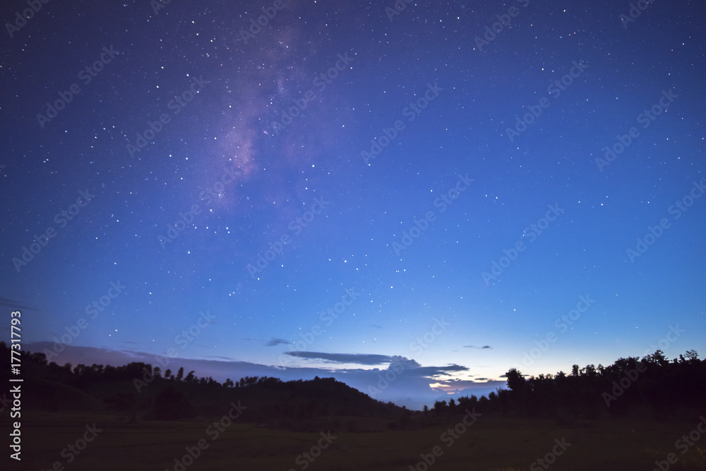 Long exposure and High ISO (800) shot of star and milky way over the silhouette mountain and rice field at dusk time to night.