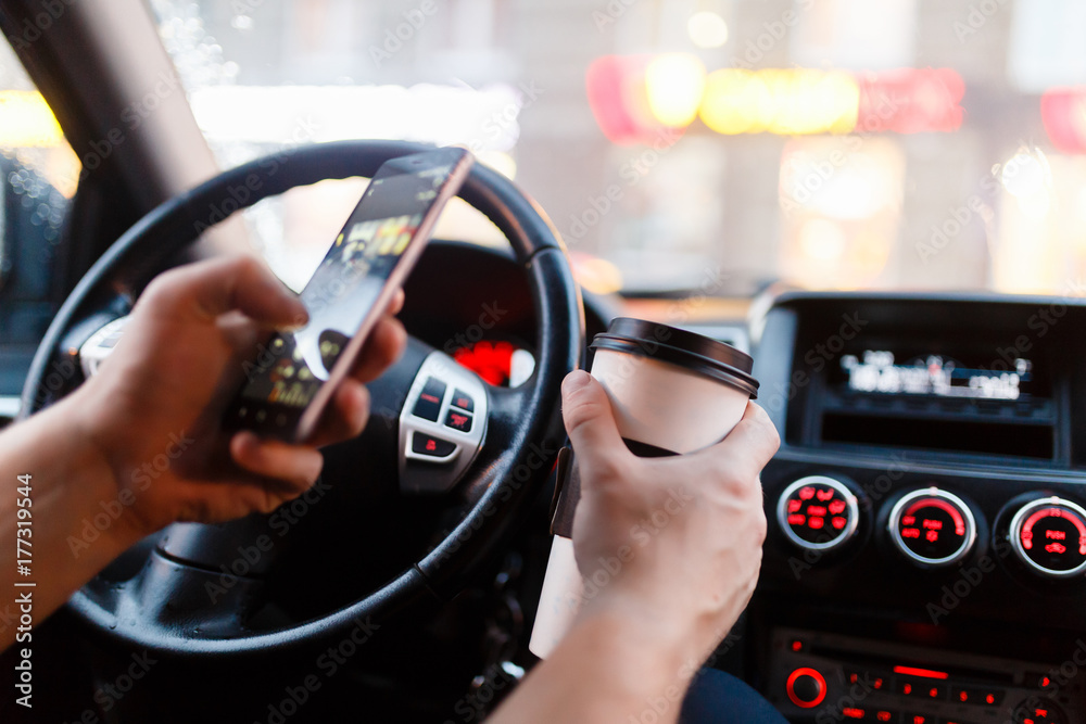 The young man makes a picture by mobile phone a Cup of coffee for social networking or a photo-sharing app. Sitting behind the wheel of a modern stylish machine in the Parking lot.