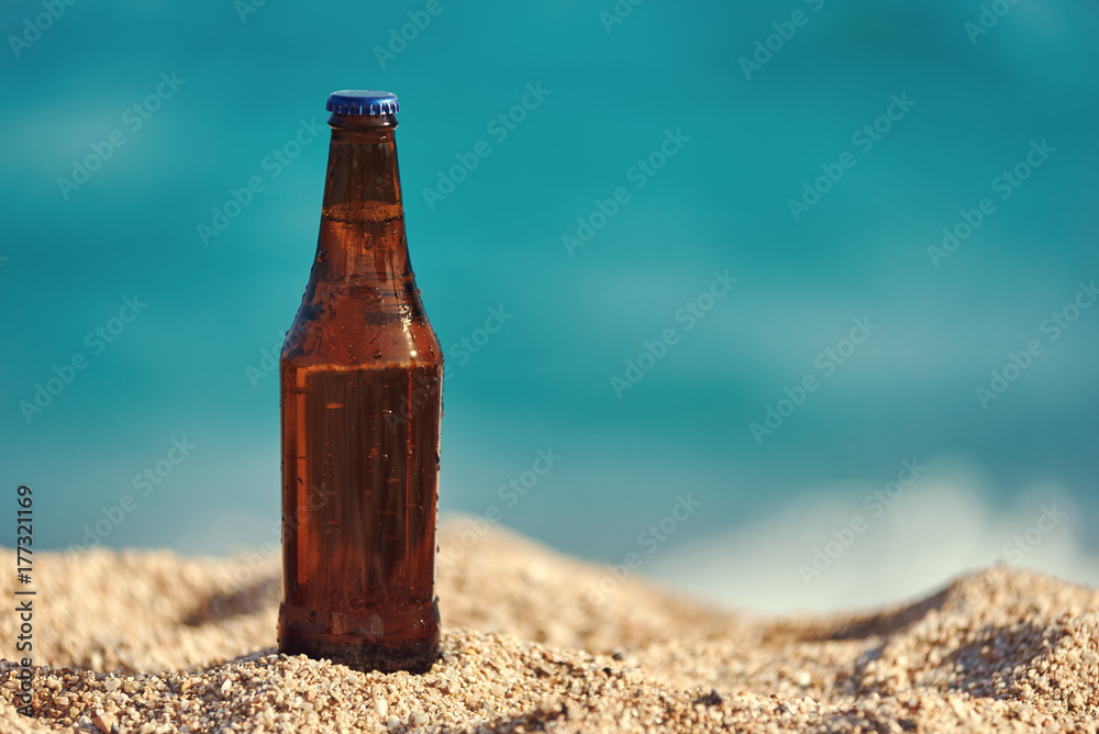 Bottle of beer on the beach sand against the sea. Bottle of beer on the beach sand against the sea.