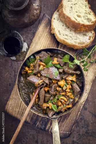 Fresh fried veal liver with chanterelle and baguette in sauce as top view in a casserole © HLPhoto