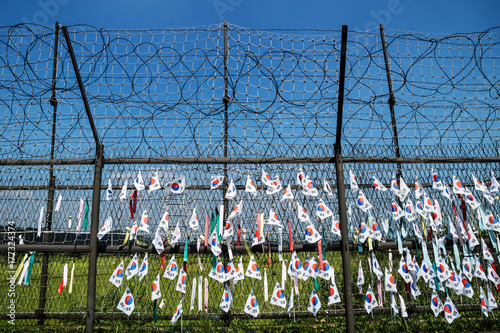 Fence with barbed wire and south korean flags at the demilitarised zone DMZ at the freedom bridge with blue sky, South Korea, Asia photo