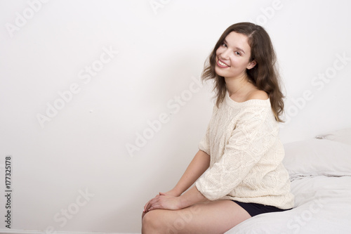 youung woman sitting on her bed looking happy